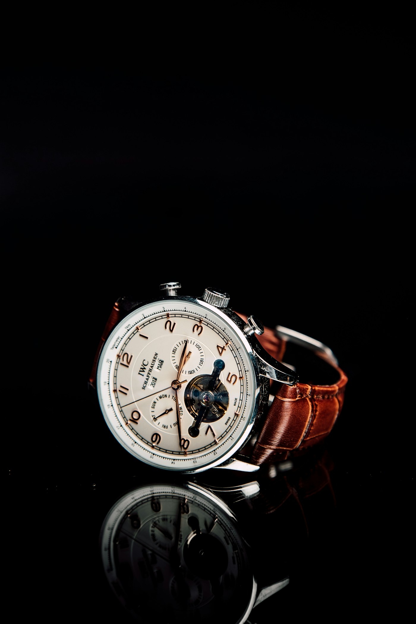A silver chronograph watch with a brown leather strap